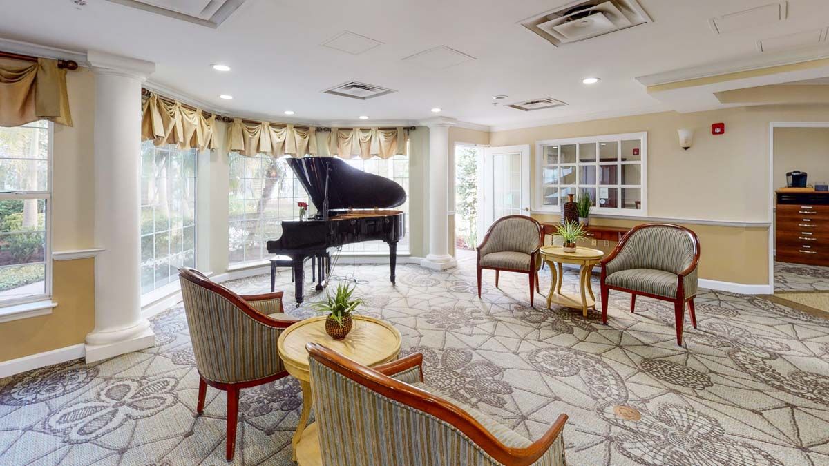 A cozy living room with a grand piano, seating area, and large windows.