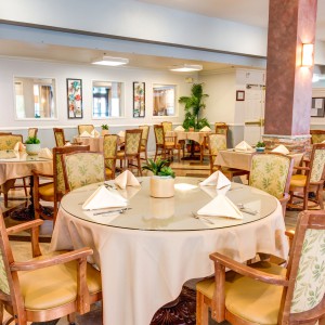 An elegantly set dining area with round tables and comfortable chairs.