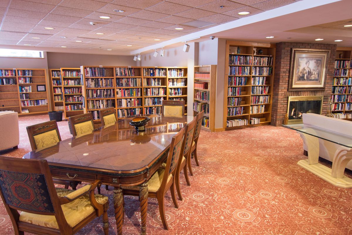 A cozy library reading room with bookshelves, a large table, and chairs.