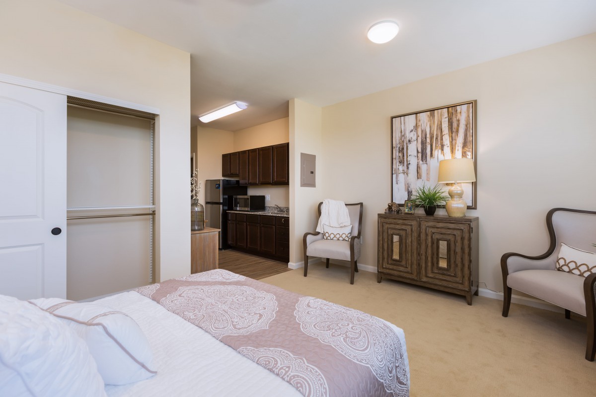 A cozy bedroom with an adjoining kitchenette, featuring stylish decor and comfortable furnishings.