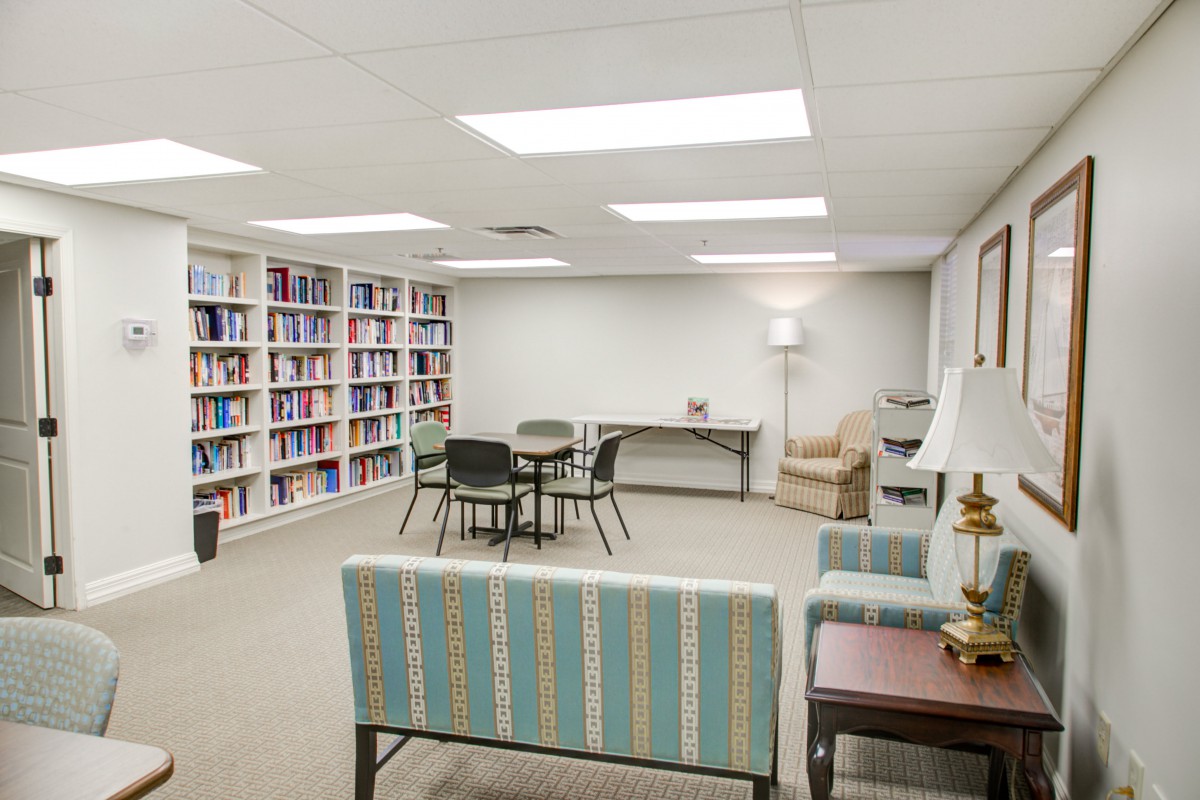 A cozy library space with bookshelves, a table, and comfortable seating.