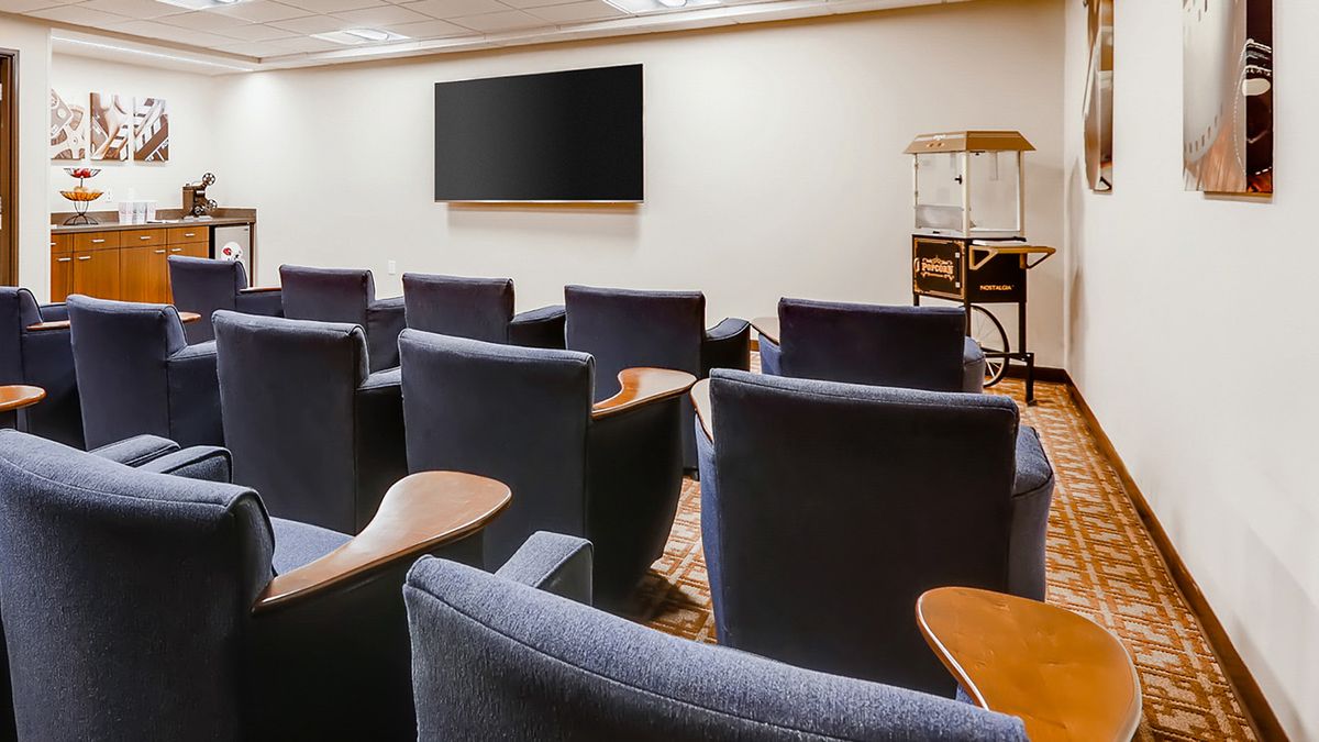 A cozy theater room with comfortable seating and a large screen, featuring a classic popcorn machine at the corner.