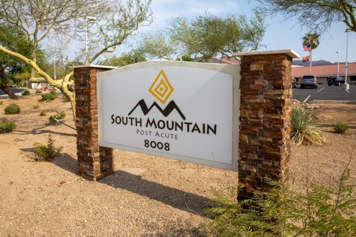 A sign for South Mountain real estate, supported by brick pillars, set in a desert landscape.