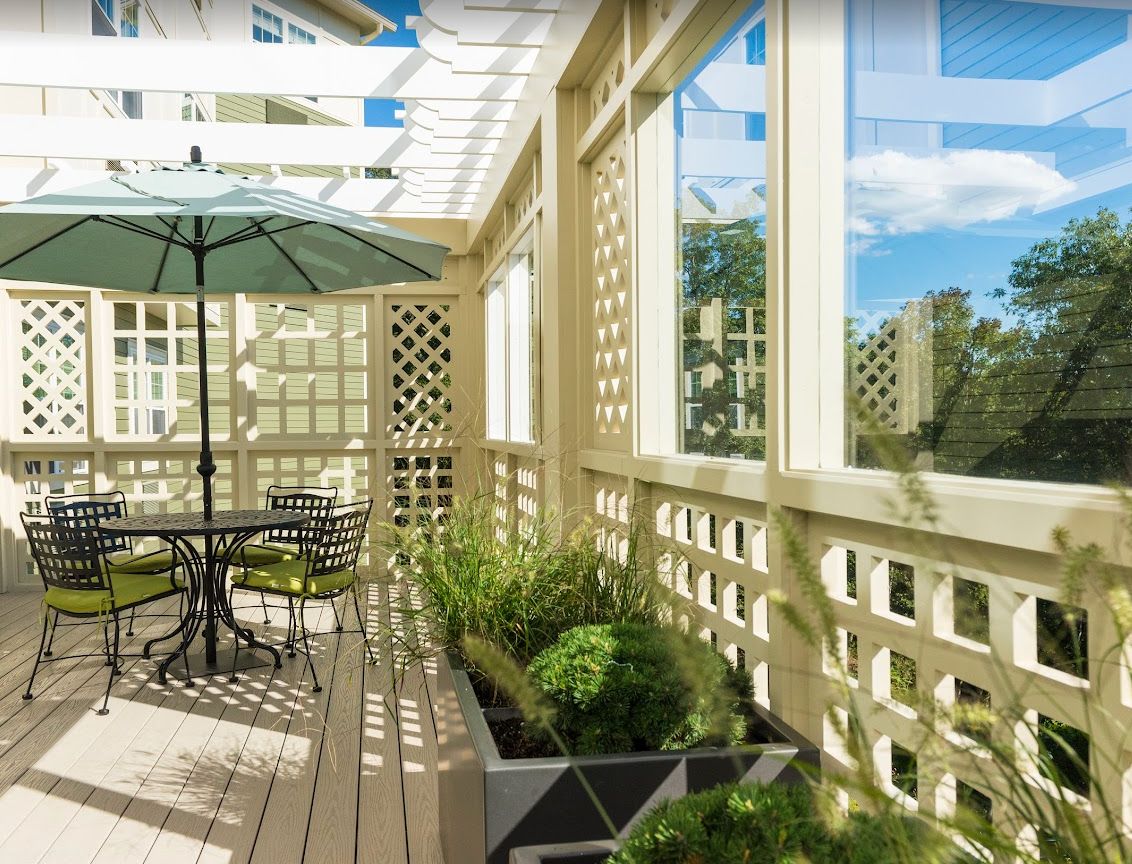 A sunny patio with a table, umbrella, and potted plants.