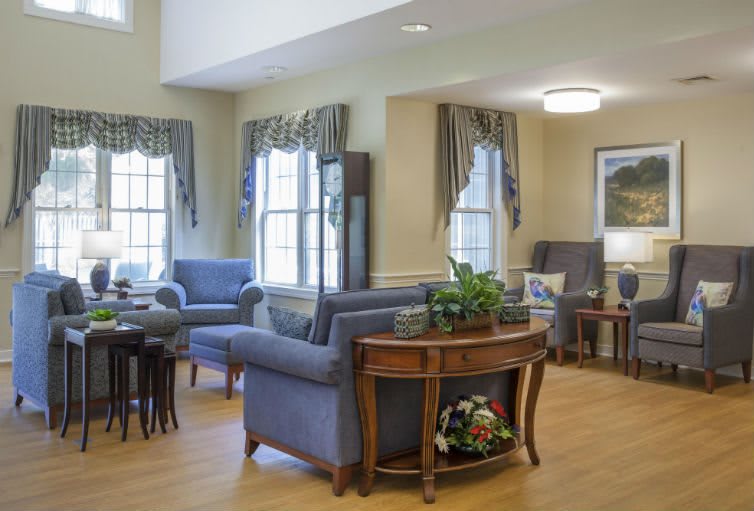 A cozy living room with classic furniture and large windows adorned with drapes.