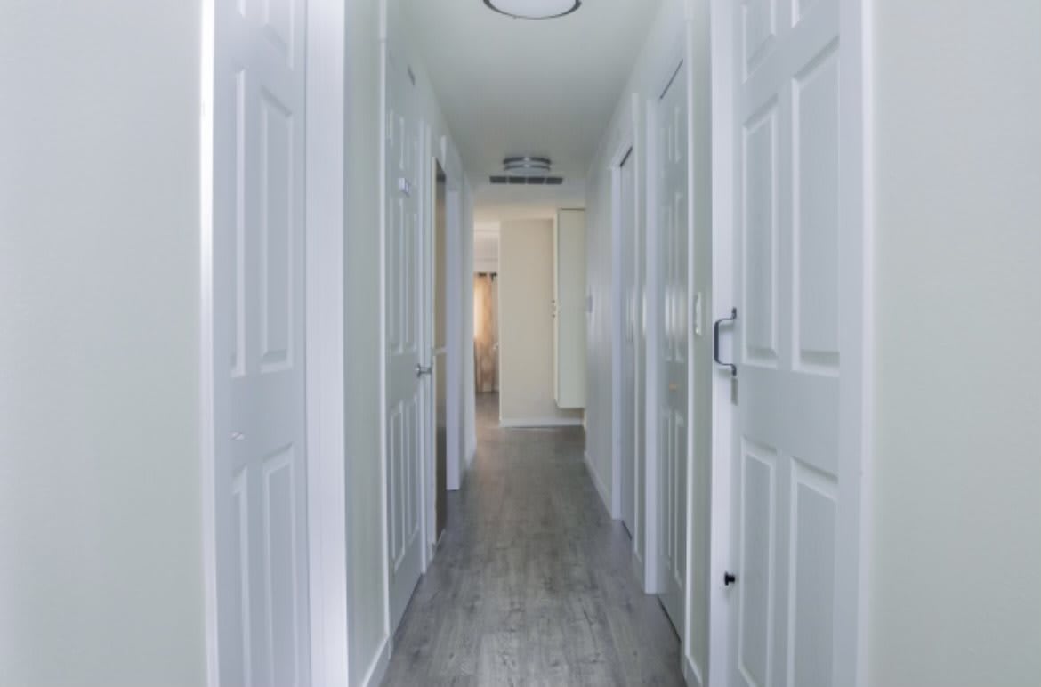 A bright hallway with multiple doors and white walls.