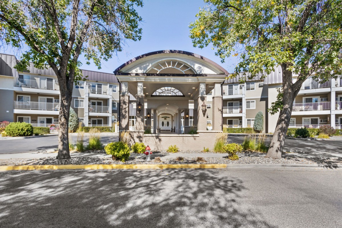 Elegant entrance to a modern apartment complex surrounded by trees.