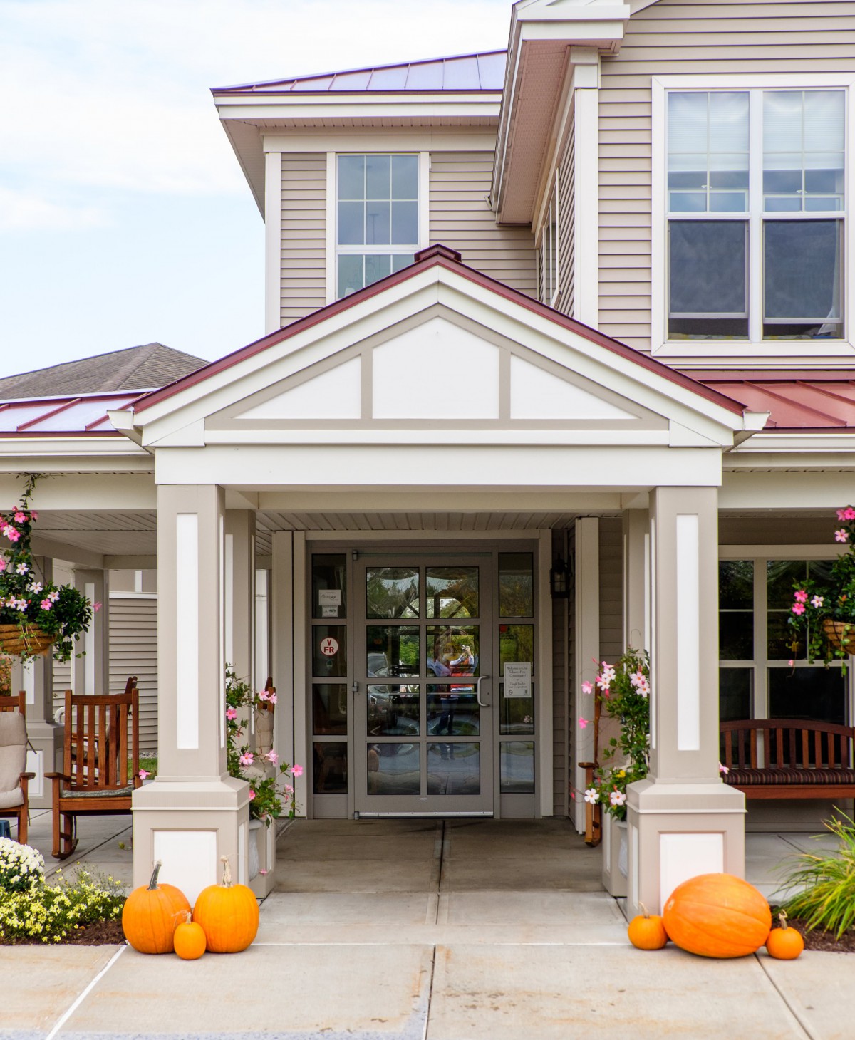 An inviting porch with pumpkins and decorations at the entrance of a building.