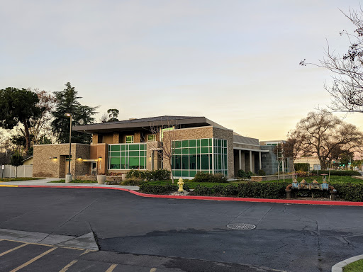 A modern commercial building featuring large glass windows and landscaped surroundings.