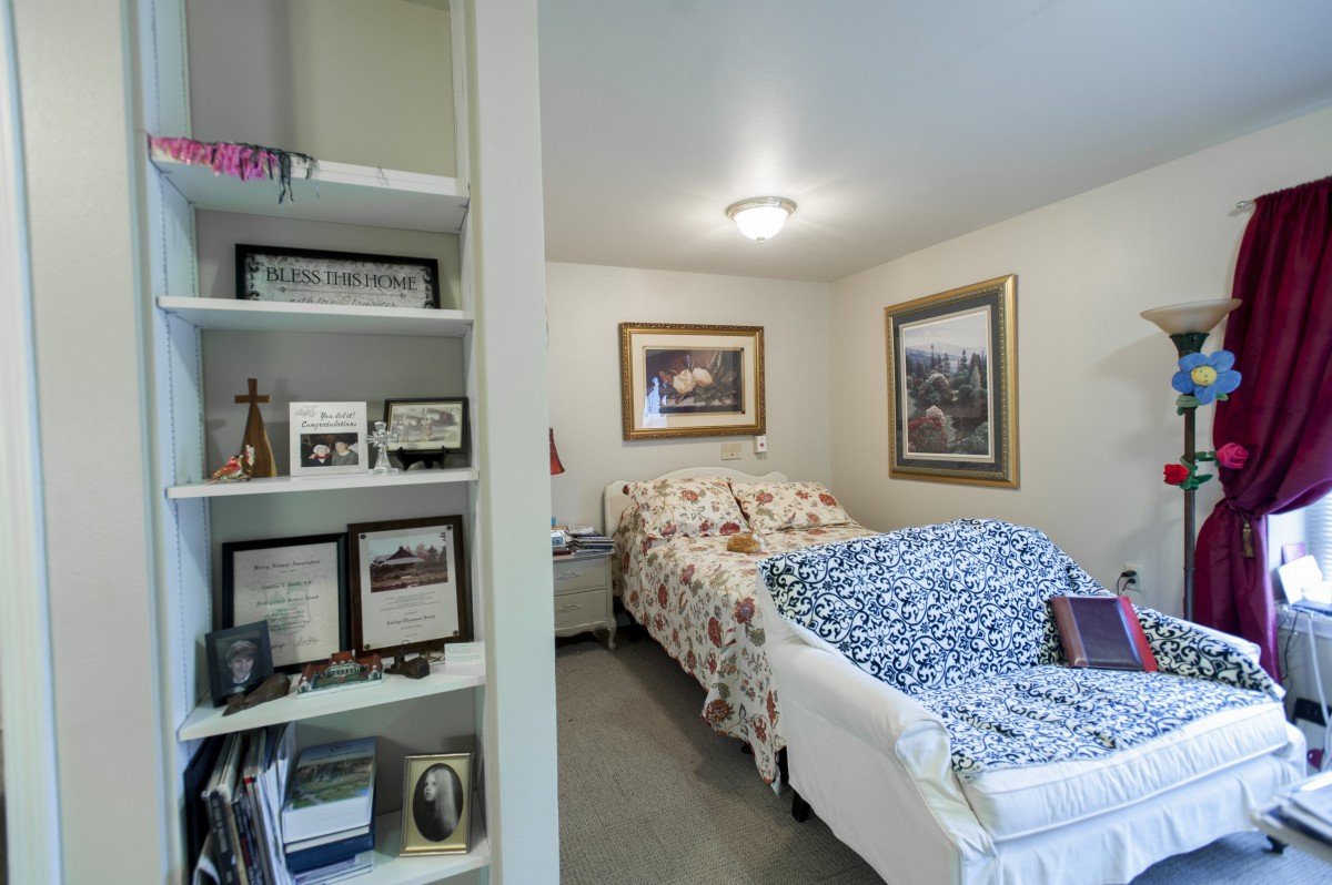 A cozy bedroom with floral bedding and decorated shelves.