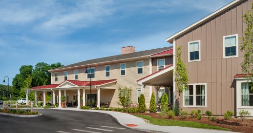 A modern residential building with a landscaped entrance under a clear blue sky.