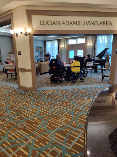 A vibrant living area featuring a piano and residents engaged in an activity.