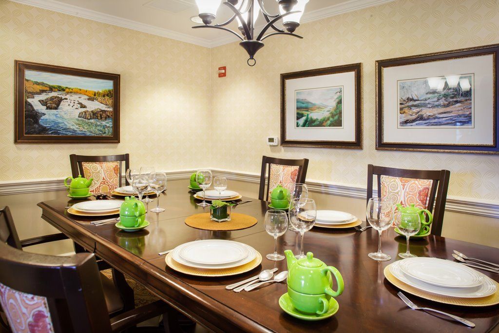 A dining room with a neatly set table and decorative green teapots.