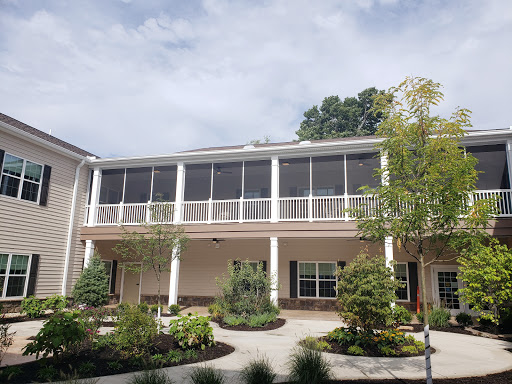 A charming residential building featuring a spacious balcony, surrounded by greenery.