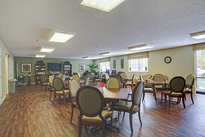 A spacious dining room with multiple tables and chairs, featuring hardwood floors and a cozy atmosphere.
