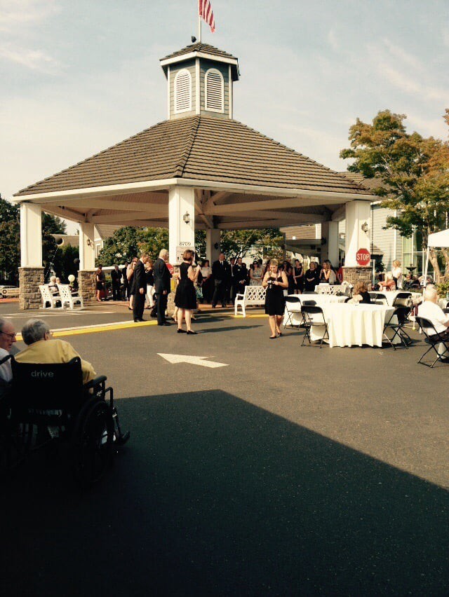A group of people gathered under a pavilion for an outdoor event on a sunny day.