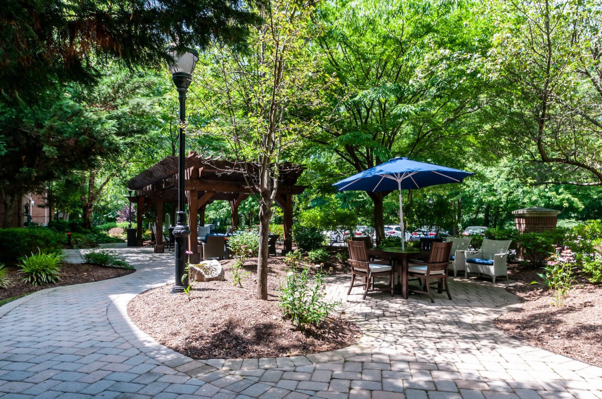 A serene park setting with a gazebo, outdoor seating, and lush greenery.