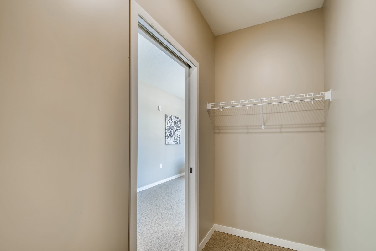 An empty closet with a sliding door and shelving in a neutral-toned room.