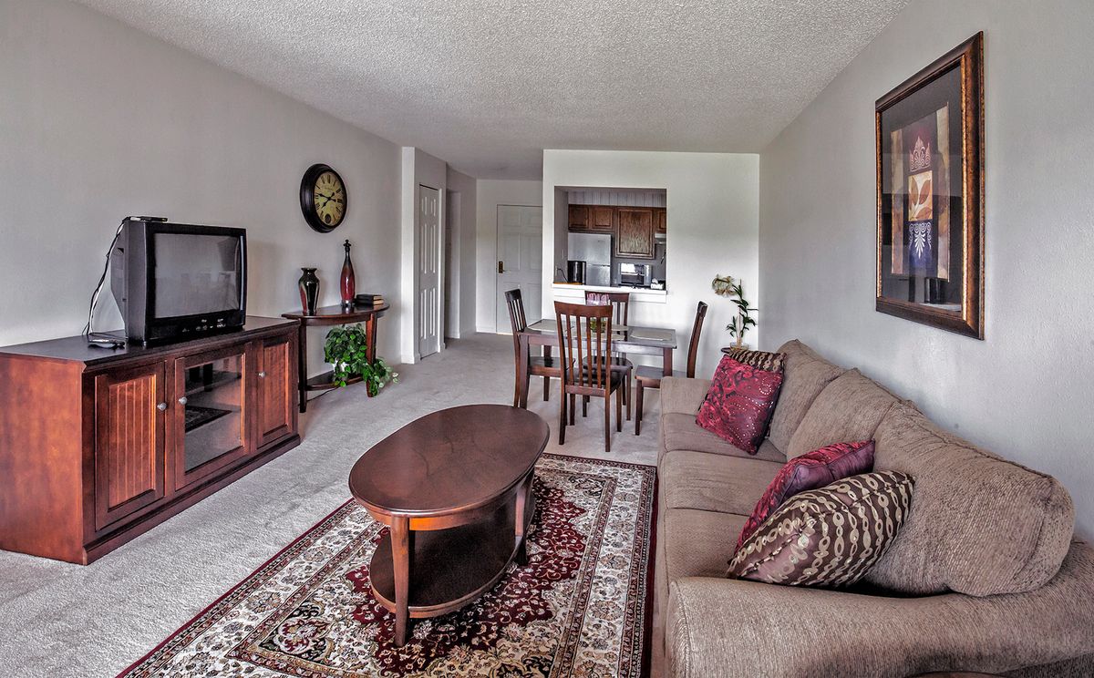 A cozy living room with a sofa, coffee table, and adjacent dining area.