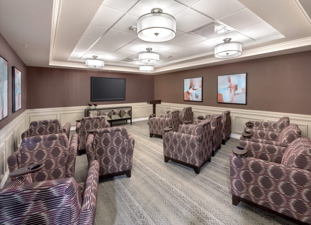 A modern lounge with patterned armchairs and a large television, suitable for meetings or small gatherings.