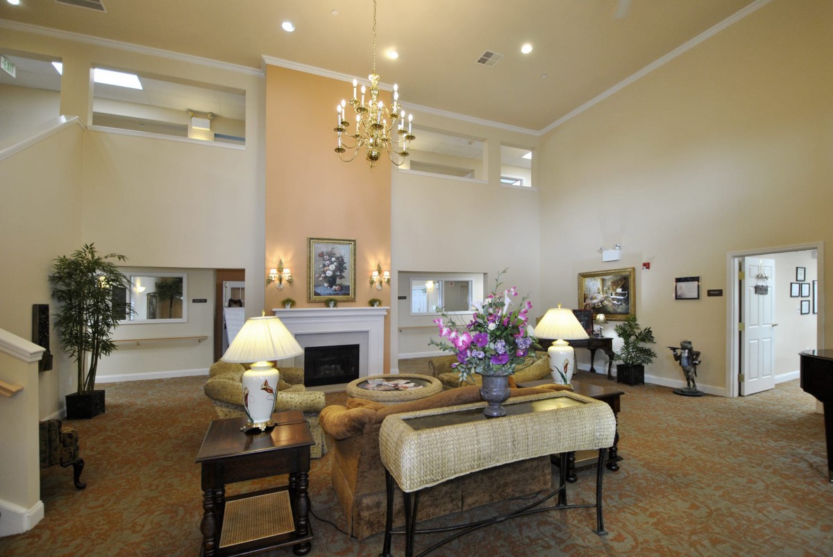 A spacious and elegantly decorated lobby with a chandelier, fireplace, and comfortable seating.