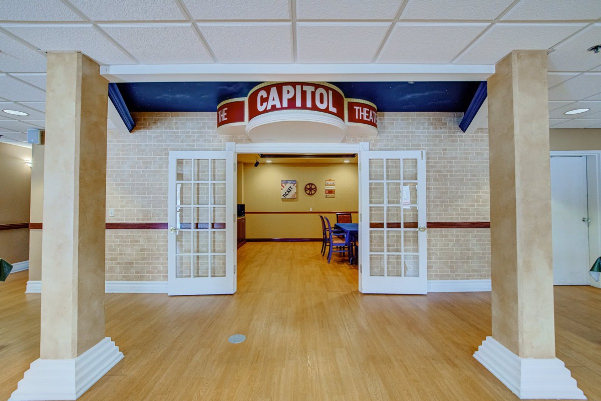 Entrance to a room with a 'Capitol' theater-style sign overhead and glass double doors.