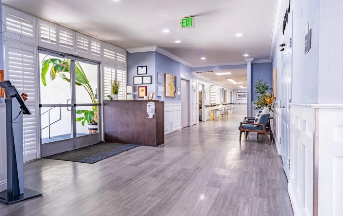A modern lobby with wood flooring and stylish decor, featuring a reception desk and hallway.
