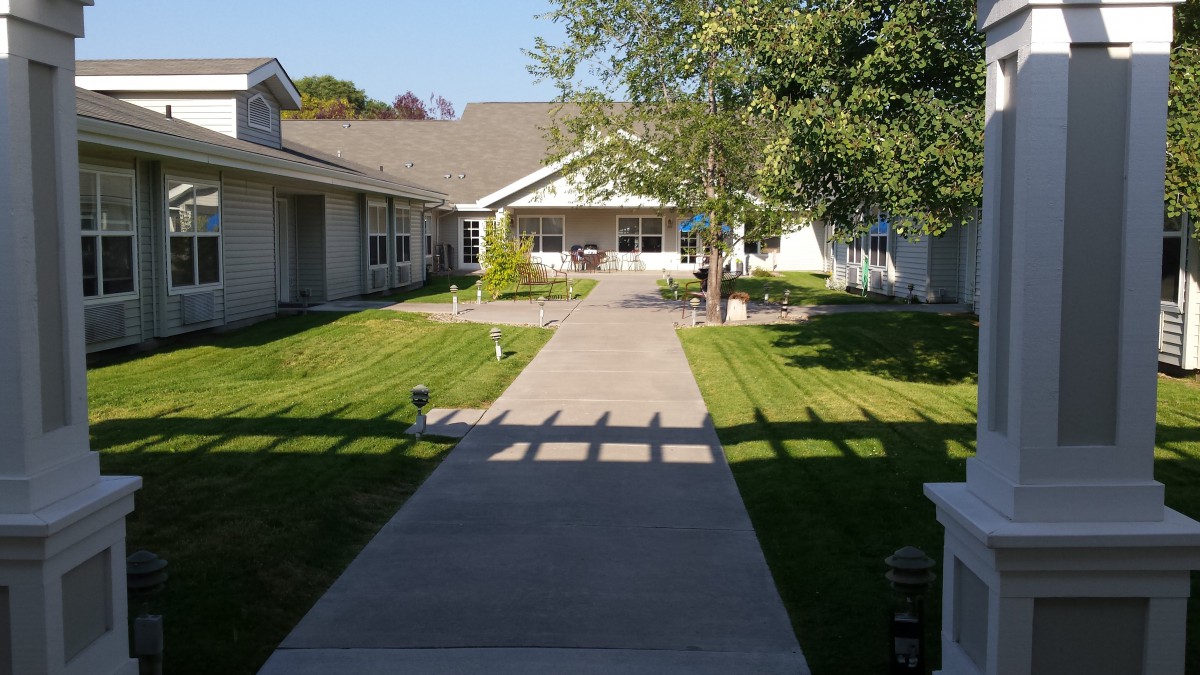 A sunny day view of a residential house with a pathway and well-maintained lawn.