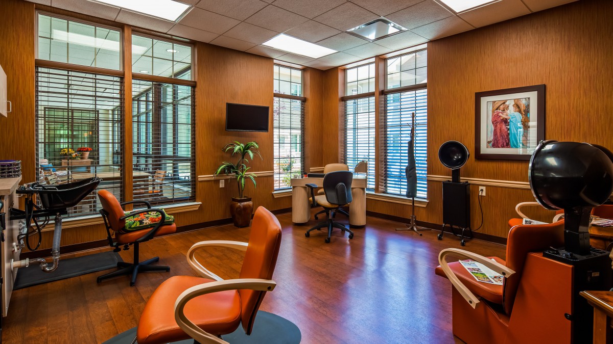 A modern office space with comfortable seating, large windows, and wooden flooring.