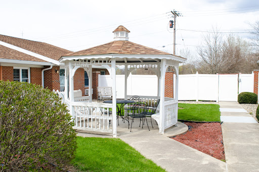 A charming white gazebo with seating, surrounded by lush green grass and a well-maintained garden.