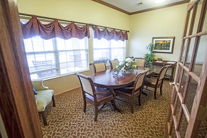 A cozy dining room with a wooden table and chairs, decorated with indoor plants and artwork.