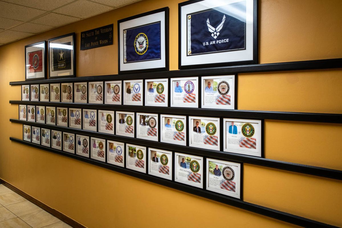 A wall displaying a collection of framed military plaques and flags.