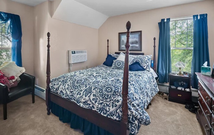 A cozy bedroom with a four-poster bed featuring blue and white bedding and tasteful decor.