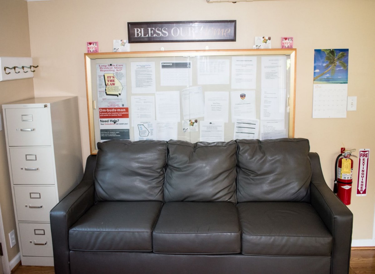 A leather couch in front of a bulletin board in an office waiting area.
