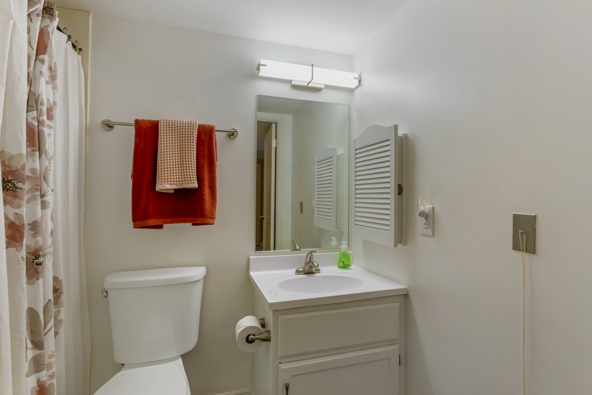 A clean and simple bathroom with a mirror, sink, and towels.