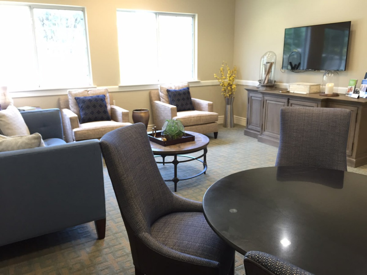 A cozy living room with comfortable chairs and a table near large windows.