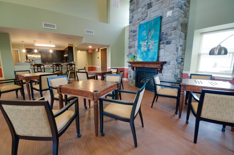 A cozy dining area with tables and chairs, featuring a fireplace and colorful artwork.