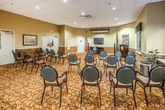 An empty conference room with chairs arranged in rows facing a projector screen.