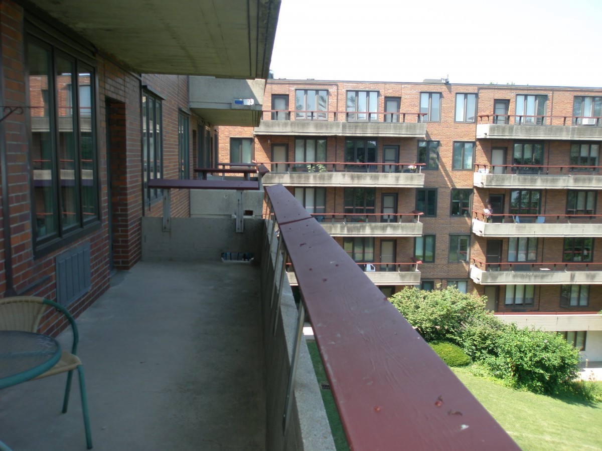 A view from a balcony overlooking an apartment complex with green space.