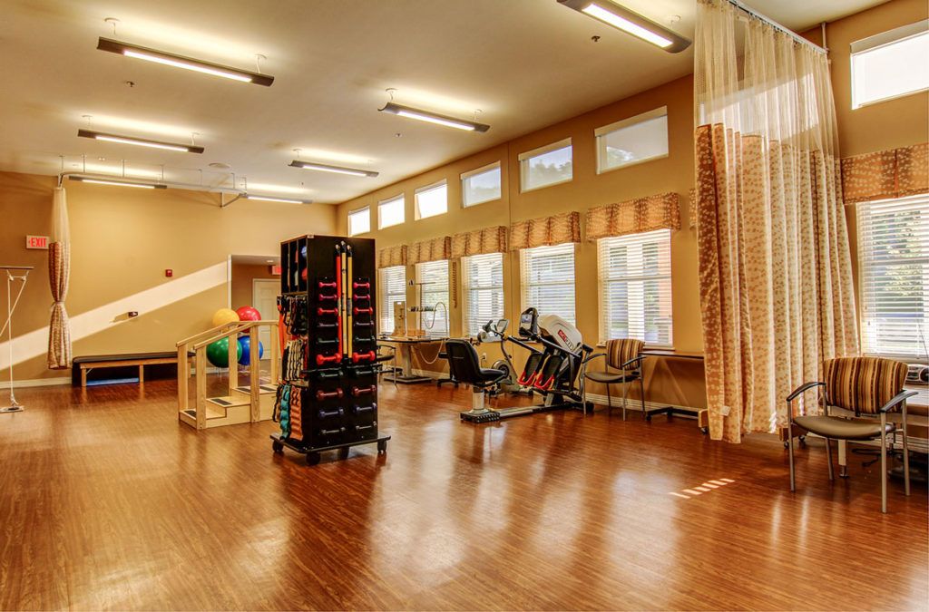 A spacious gym featuring various exercise equipment and ample natural light.