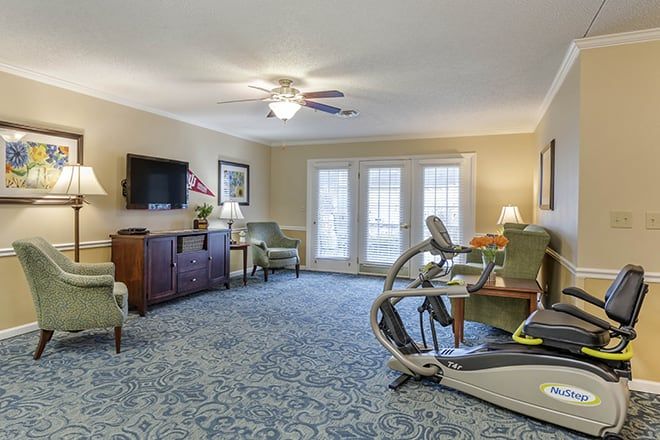 A cozy living room featuring exercise equipment, a television, and comfortable seating.