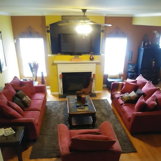 A cozy living room with red sofas, a fireplace, and a television.
