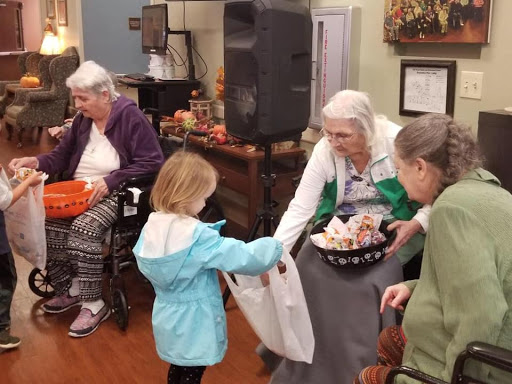 A heartwarming moment as a young girl presents a gift to an elderly resident during a community event.