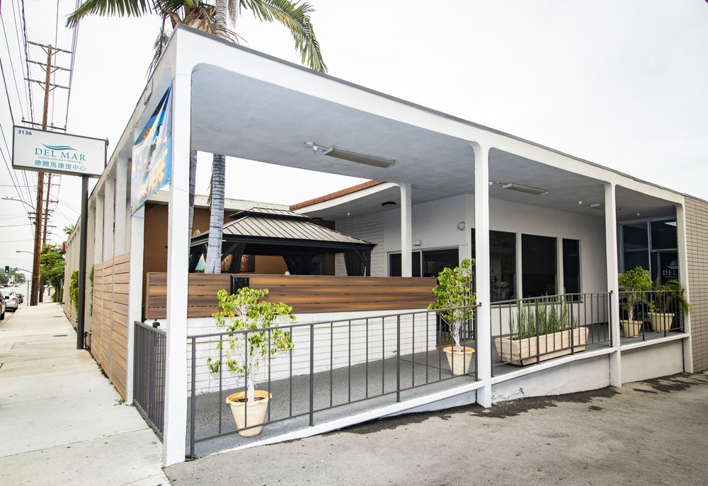 A modern building with a covered porch in a tropical setting.
