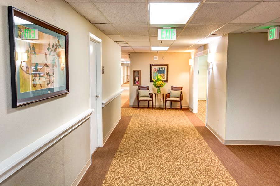 A well-lit hallway with chairs and artwork on the walls.