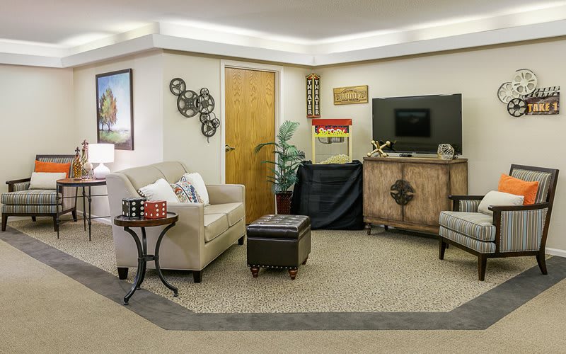 A cozy living room featuring a sofa, chairs, and a TV with a popcorn machine for entertainment.