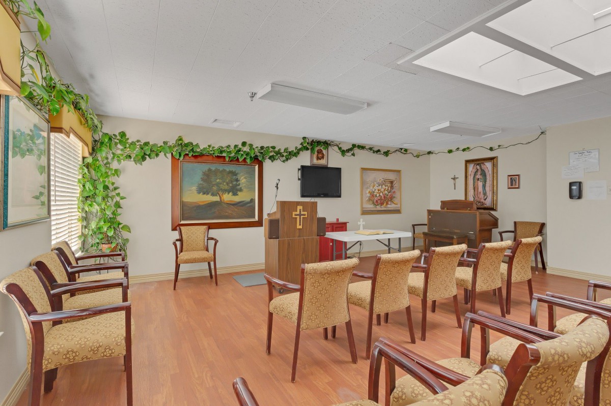 A small chapel with seating, artwork, and greenery.