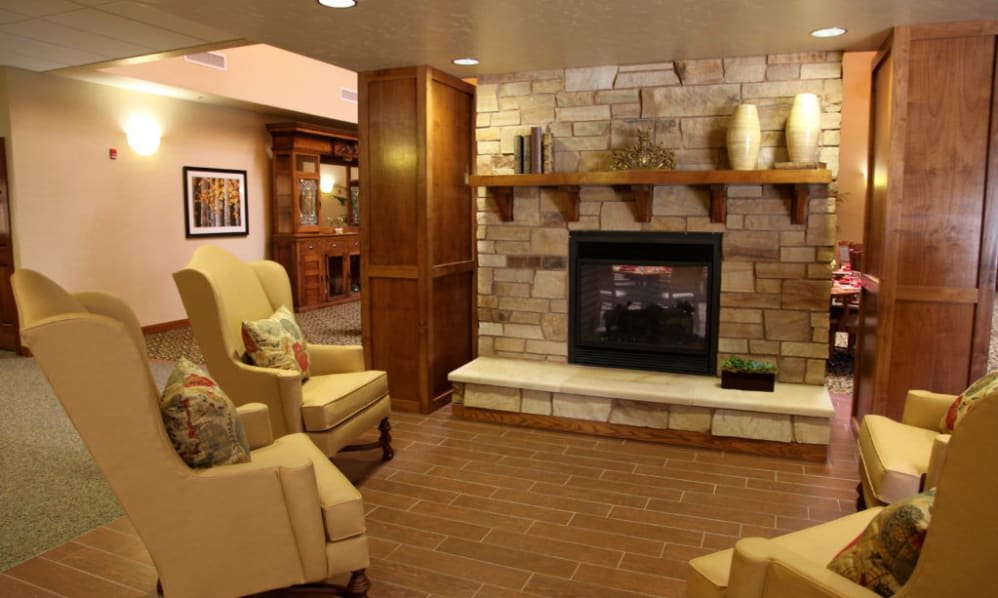 A cozy living room featuring a fireplace, armchairs, and wooden accents.