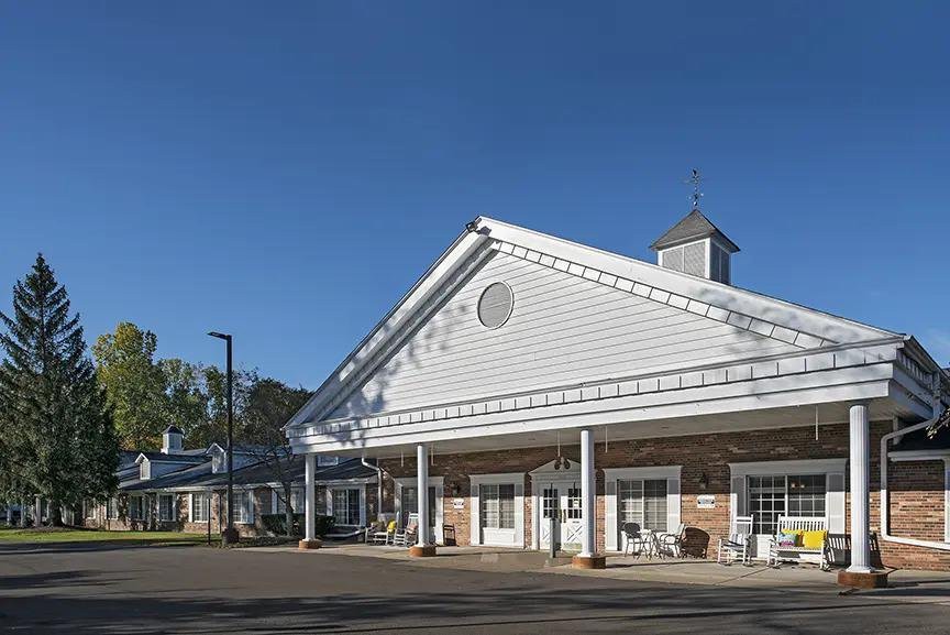 A sunny view of a residential building with a porch and classic architecture.