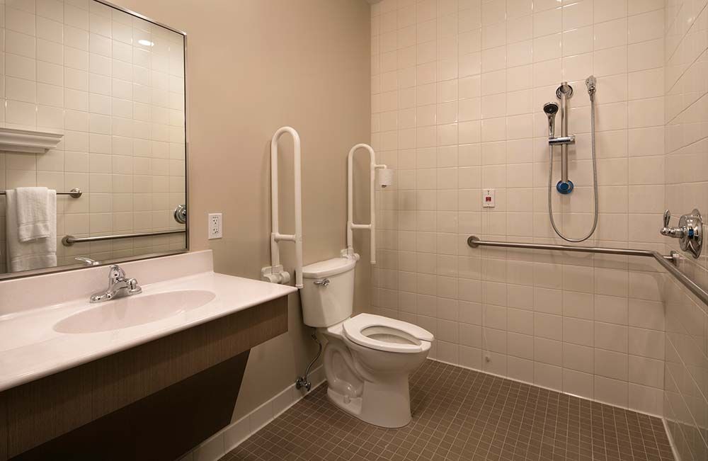 An accessible bathroom with grab bars, a toilet, and a sink.